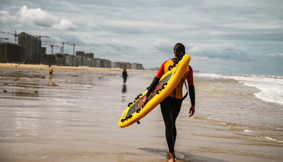 Surfer carrying a board on Ostend beach, Belgium
