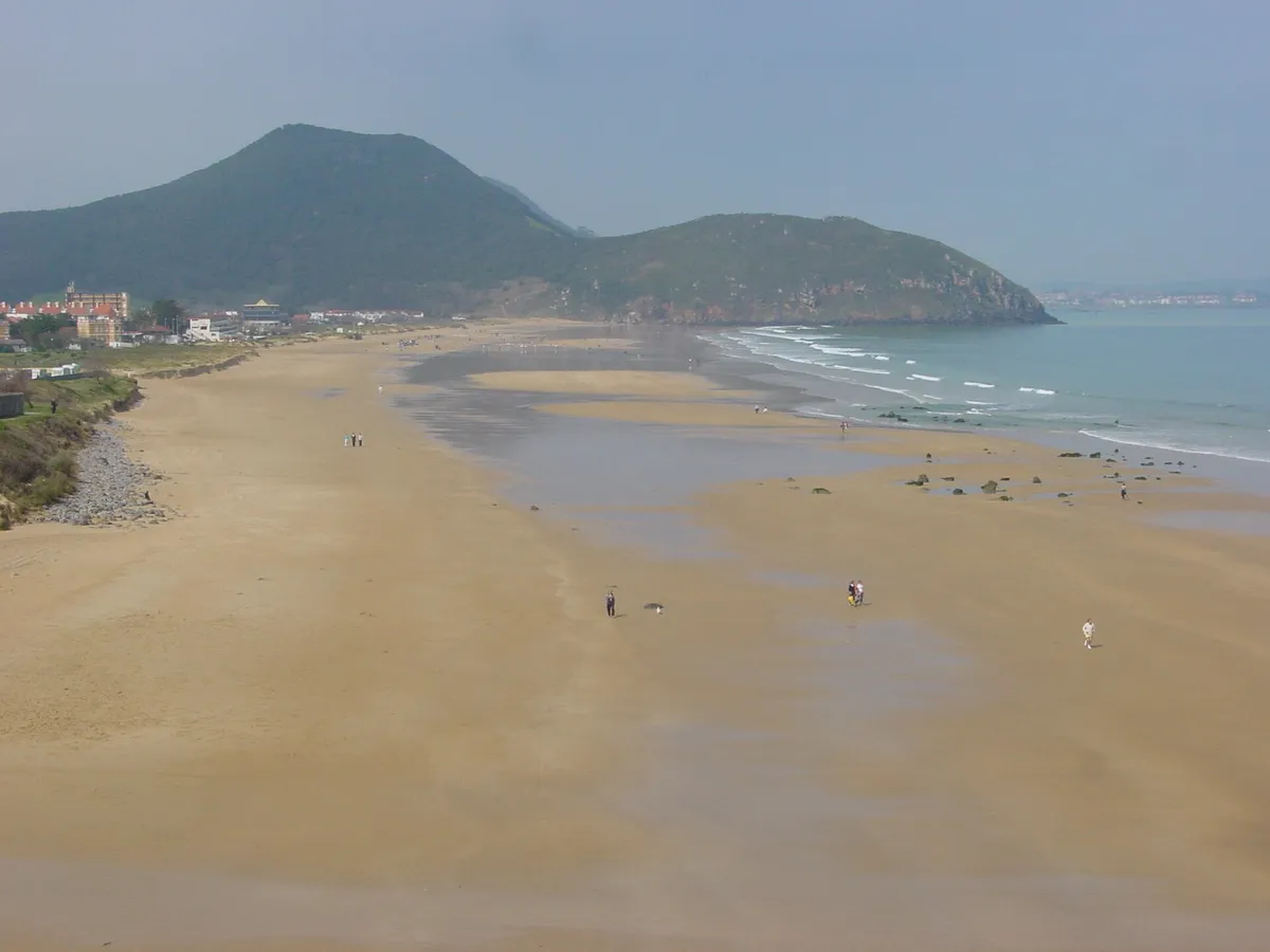 Vista elevada de la playa de Berria, con arena amplia y un monte verde al fondo