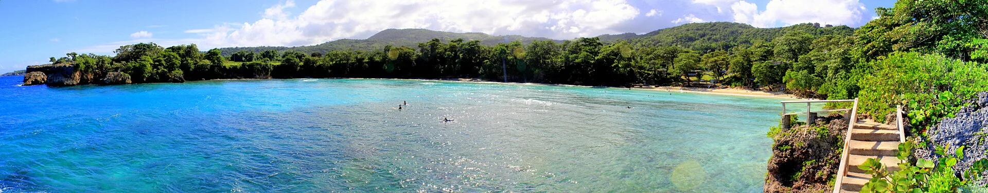 Panorama of Boston Bay, Portland, Jamaica, with surfers in the water and the beach on the right