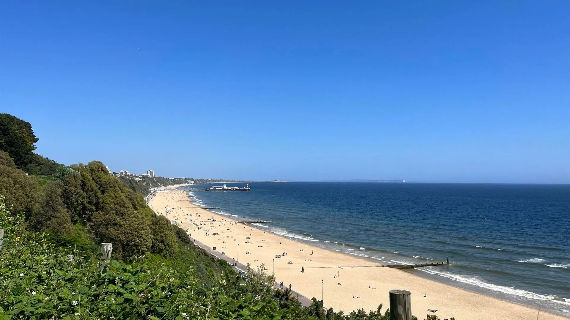 Looking along Bournemouth's sandy beach from the cliff top with a pier in the distance