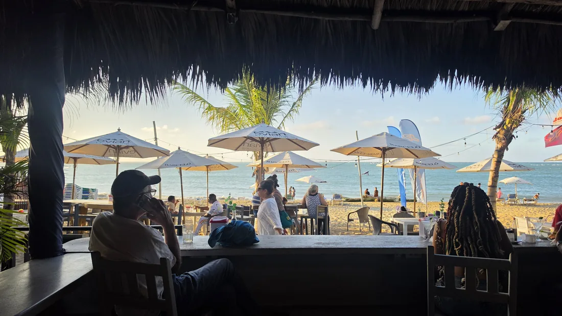 Vue depuis un bar de plage sous paillote à Cabarete Bay, parasols et mer en fin de journée