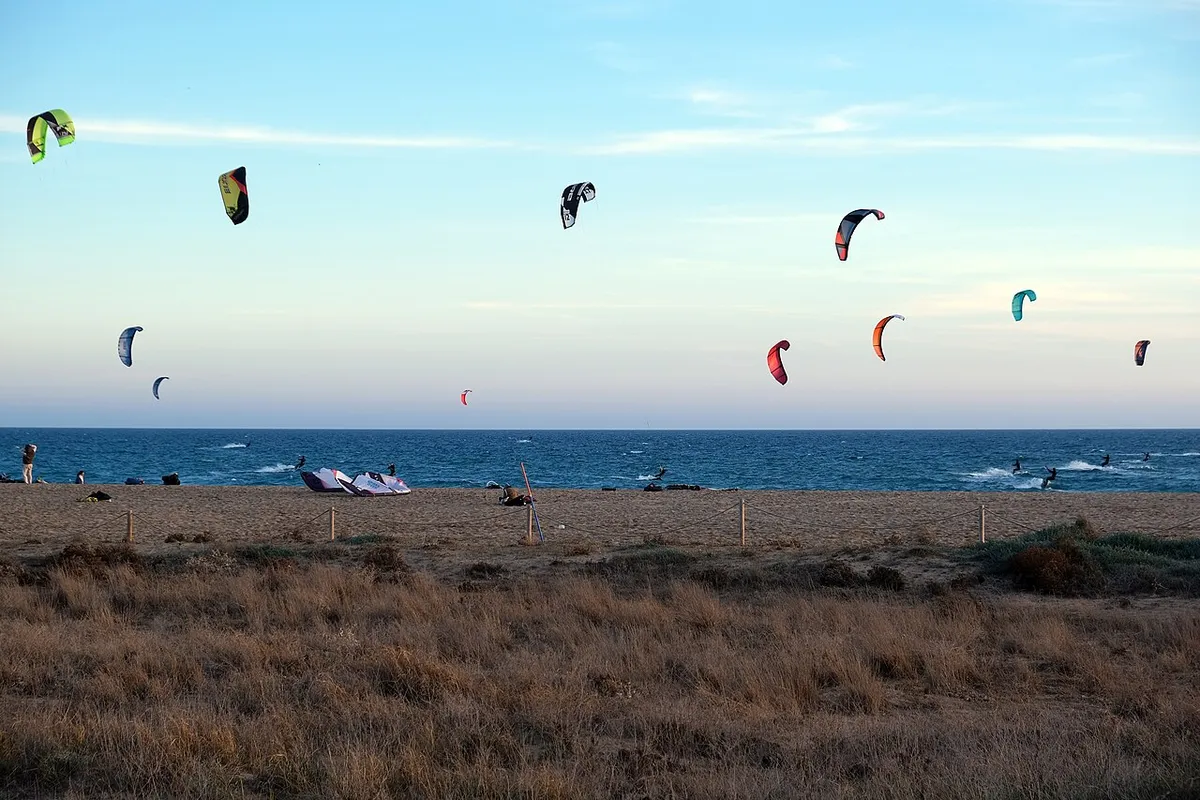 Kitesurf kites over Castelldefels beach in the late afternoon, with gear laid out on the sand