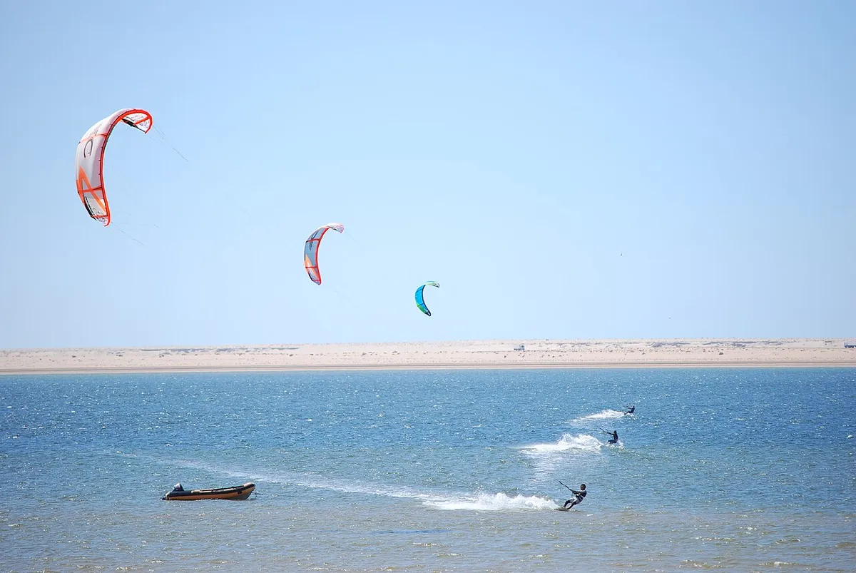 Kitesurfistas sobre aguas azules en Dakhla, con una franja de arena al fondo
