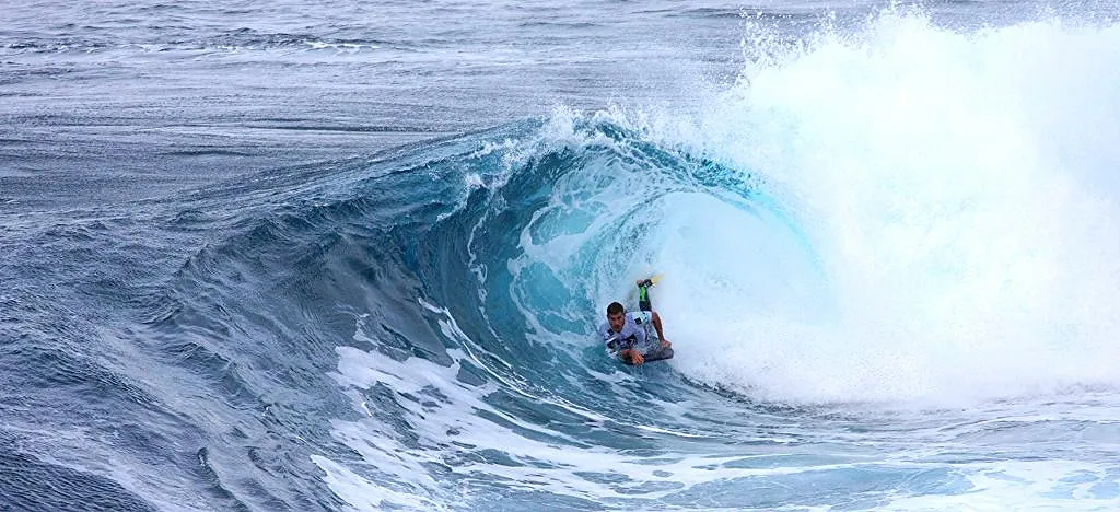 Bodyboarder inside the barrel of a large, hollow blue wave