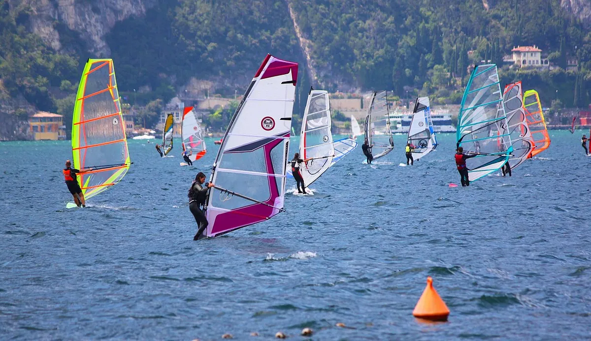 Windsurfistas en el lago de Garda frente a Torbole, con una boya naranja en primer plano