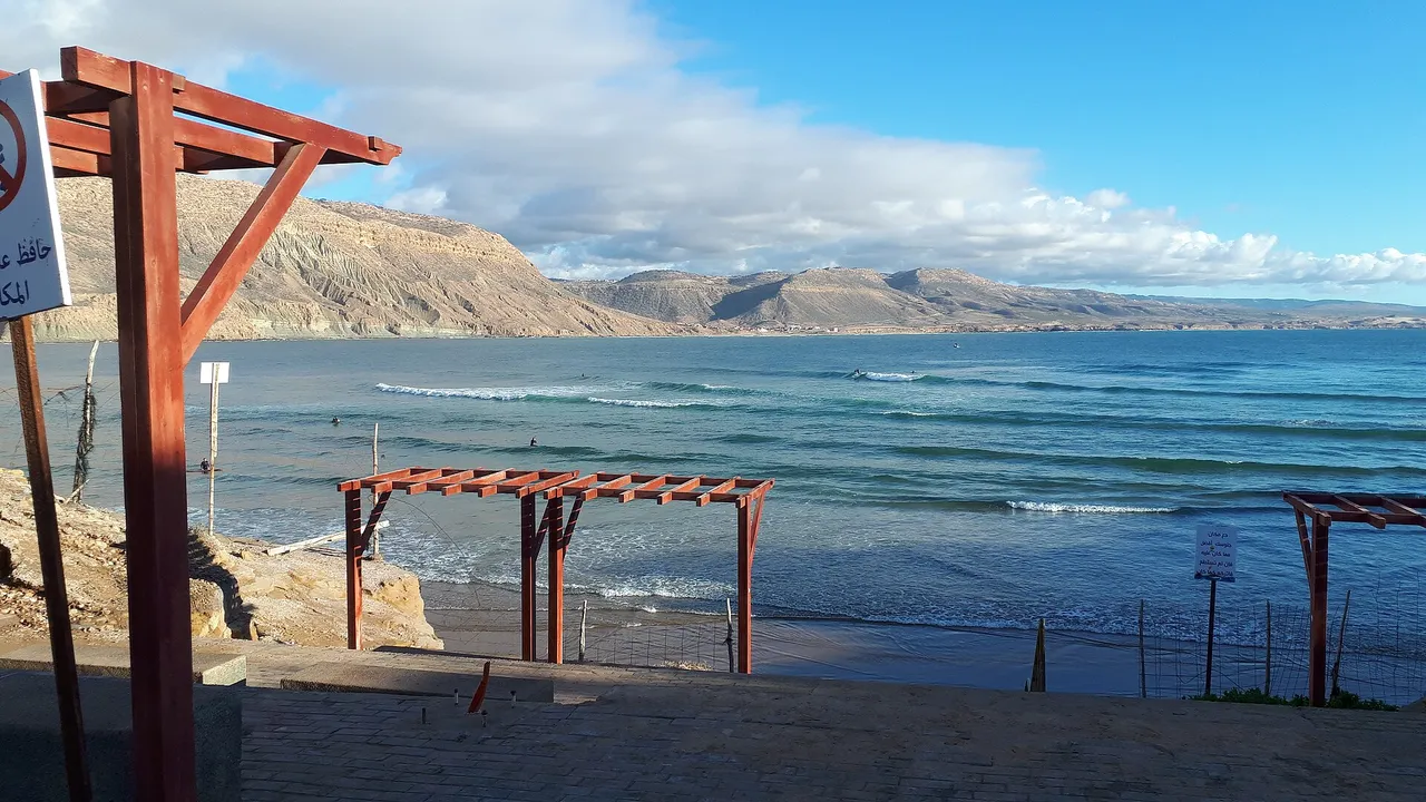 Lignes de houle et surfeurs dans la baie d'Imsouane, avec des falaises en arrière-plan