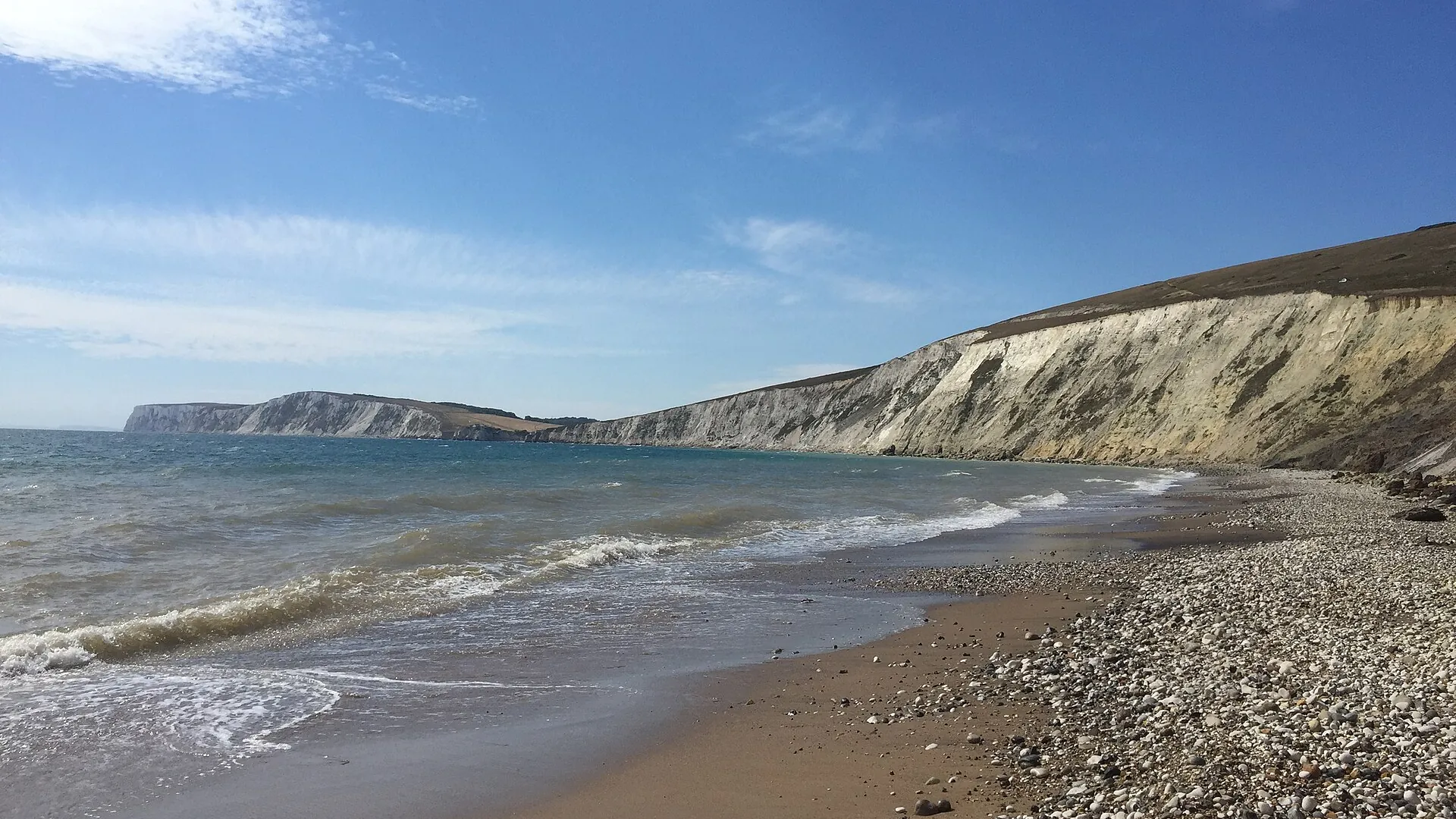 Small waves breaking on Compton Bay beneath the chalk cliffs of the Isle of Wight