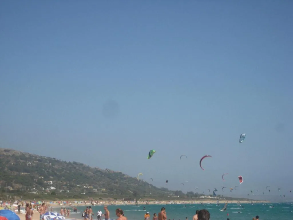 Decenas de cometas de kitesurf sobre la playa de Valdevaqueros, en Tarifa, con bañistas en la orilla