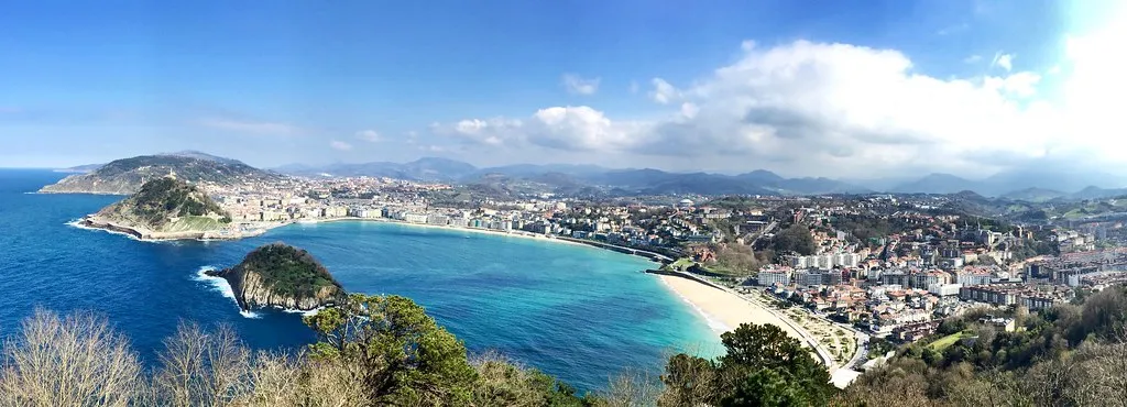 Panorama of La Concha bay and the city of San Sebastián seen from a hilltop, with Santa Clara island in the bay