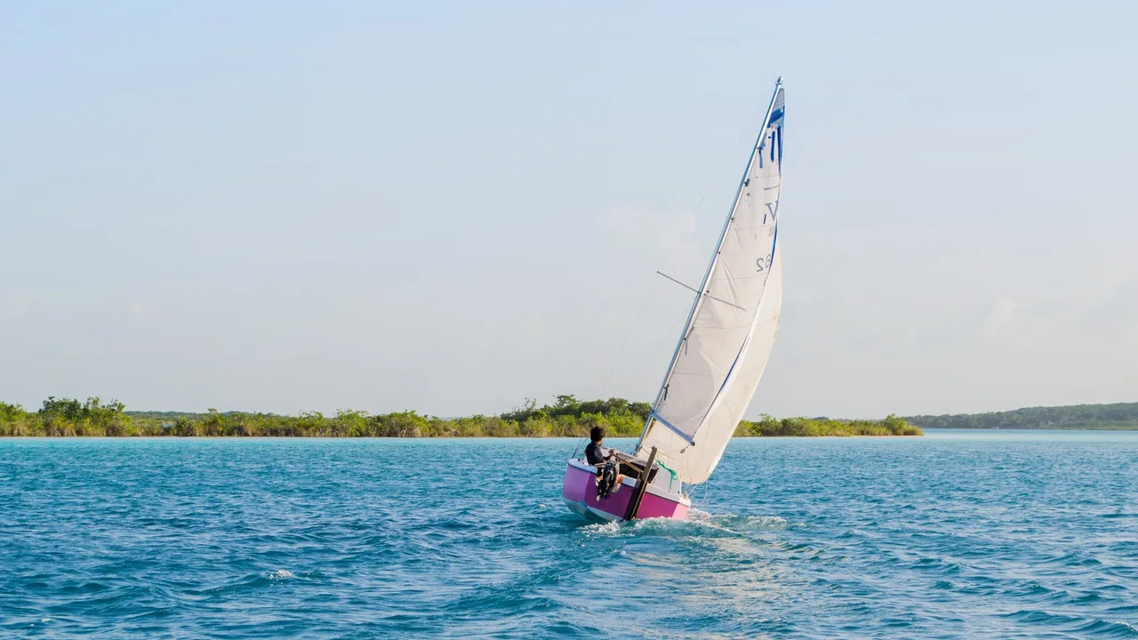 A small sailboat on the turquoise water of Laguna Bacalar, Quintana Roo, Mexico