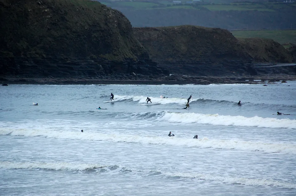 Surfers riding a wave at Lahinch, County Clare