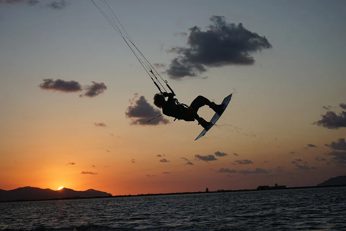 Kitesurfeur en plein saut, en silhouette sur un ciel de coucher de soleil, à Lo Stagnone