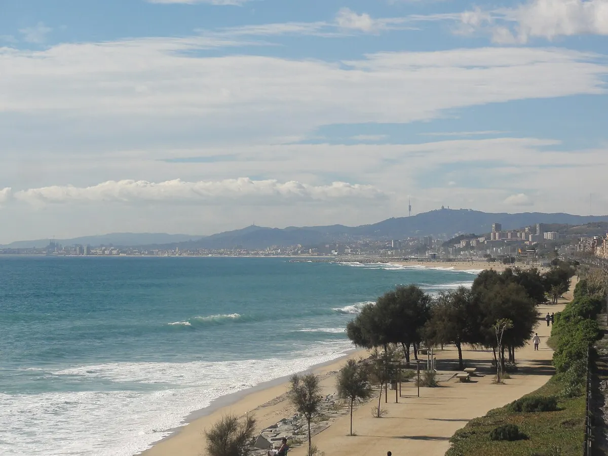 El Masnou beach with surf and pines beside the promenade, and the coastline beyond