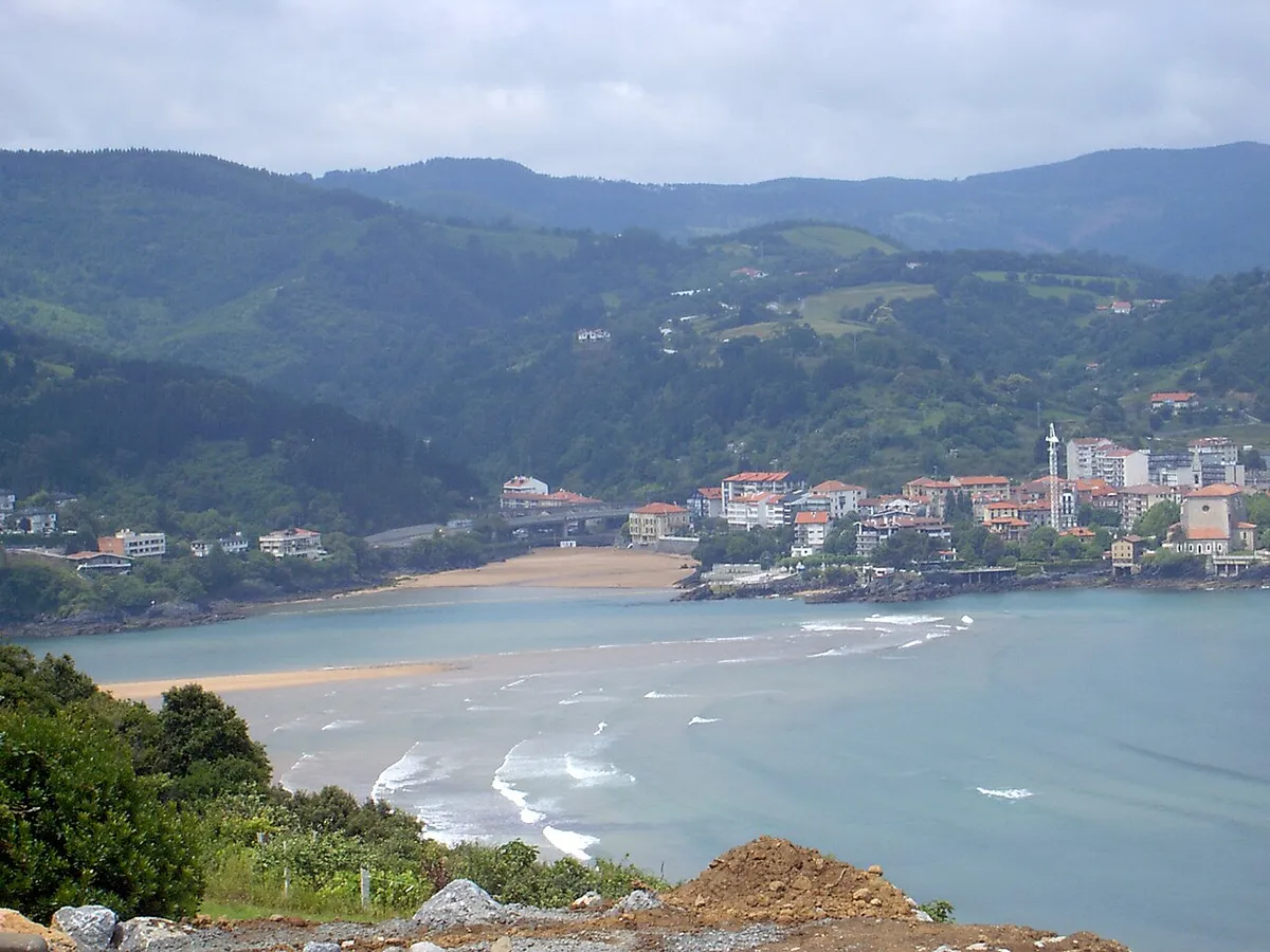 Vue de Mundaka et de l'embouchure de l'estuaire, avec des vagues et des collines vertes au fond