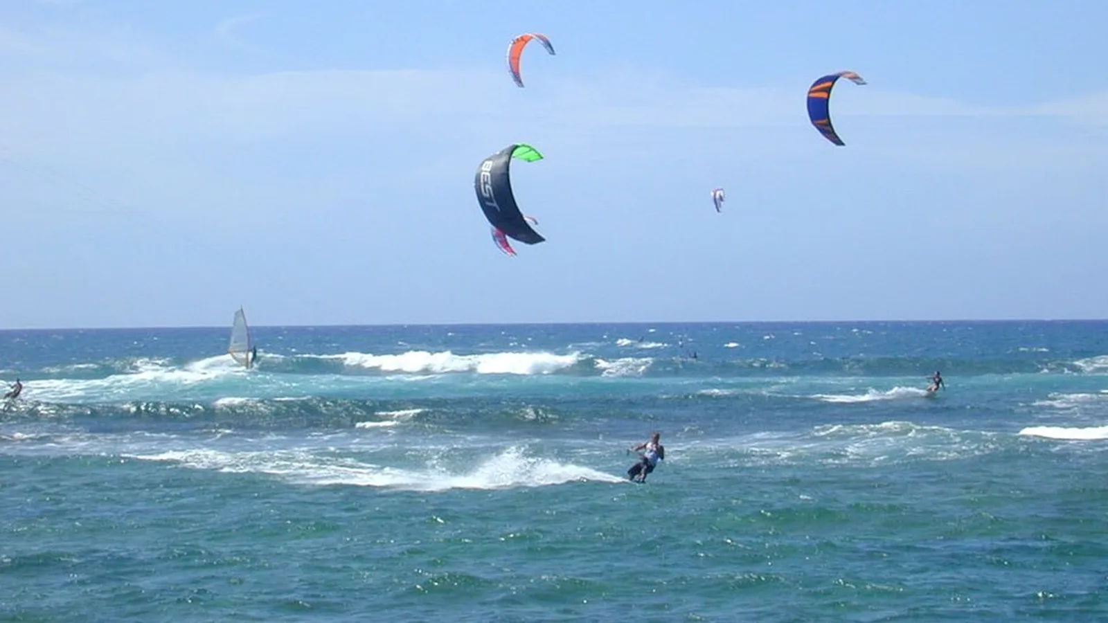 Kitesurfers and a windsurfer in the waves off Oahu, Hawaii