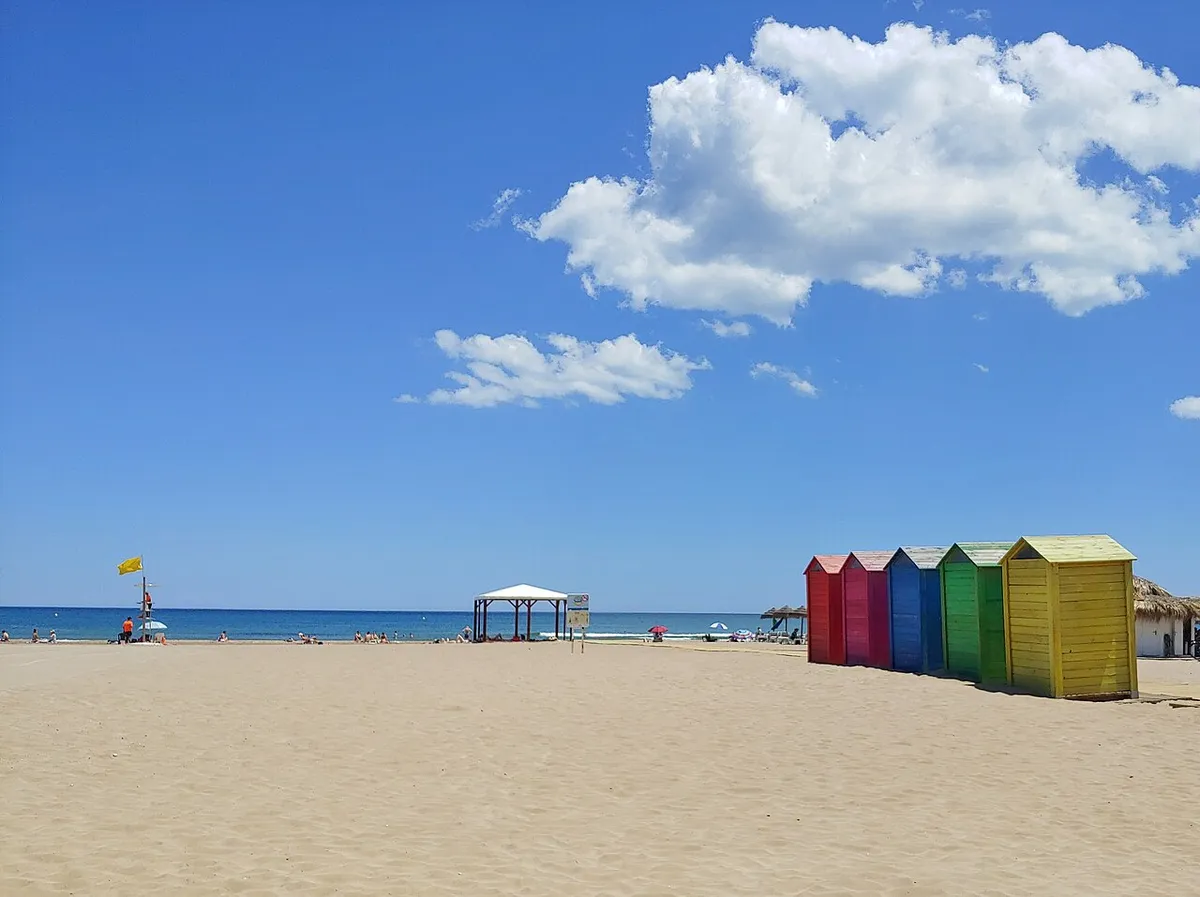 Playa de arena de La Patacona con casetas de colores y el mar al fondo