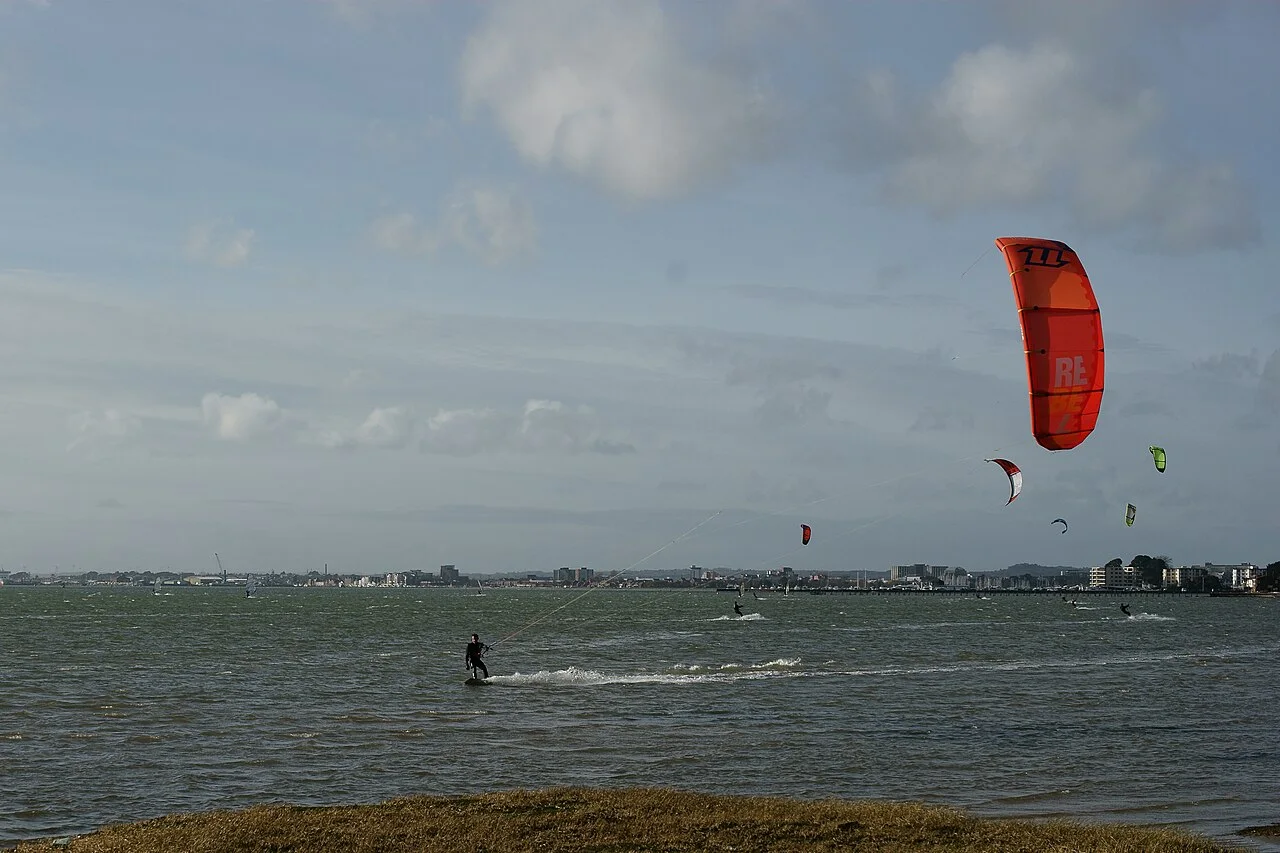 A kitesurfer riding in Poole Harbour, Dorset, near Canford Cliffs