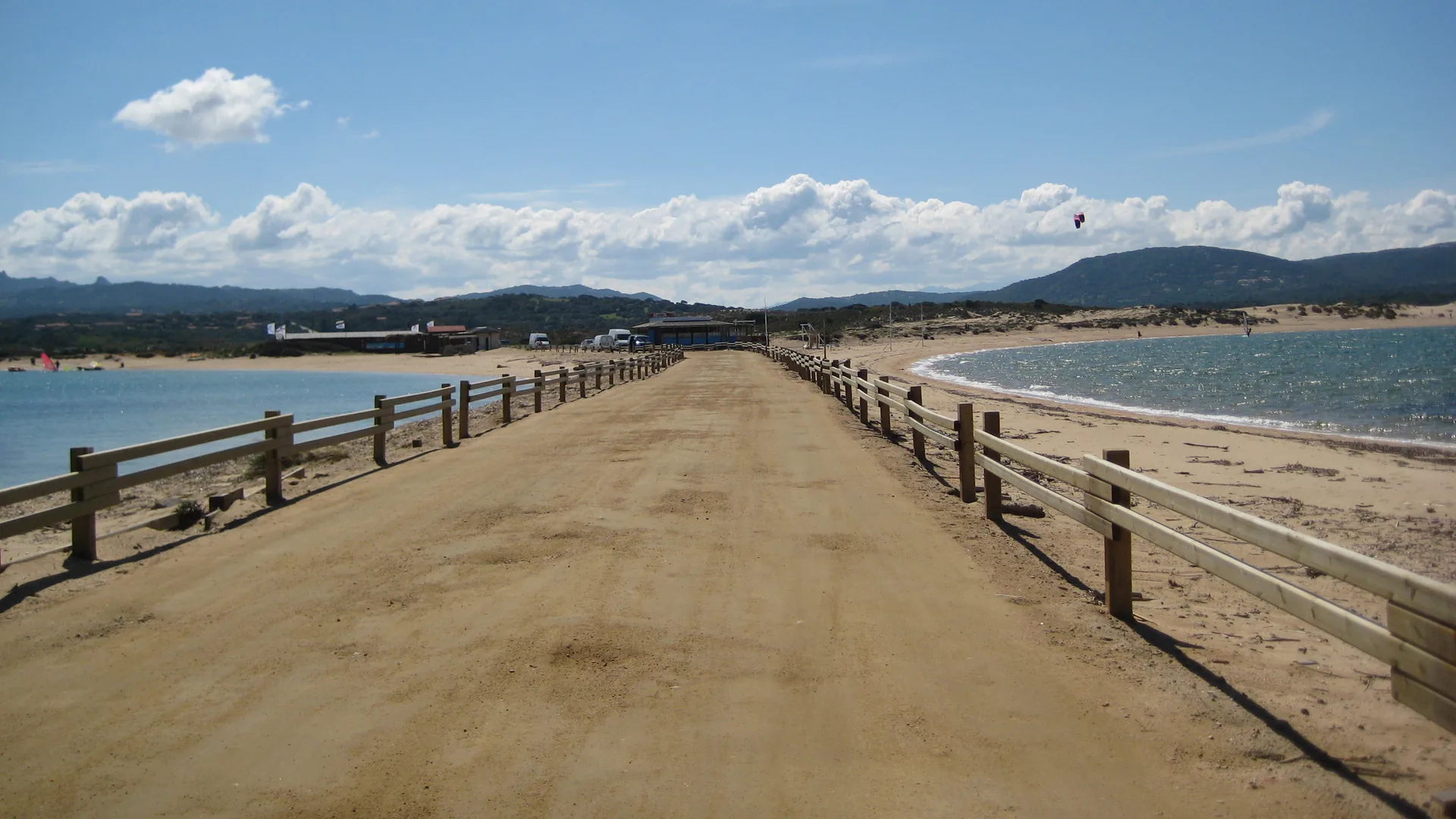 The Isola dei Gabbiani isthmus between the two bays of Porto Pollo, Palau, Sardinia, with a kite and windsurf sails visible