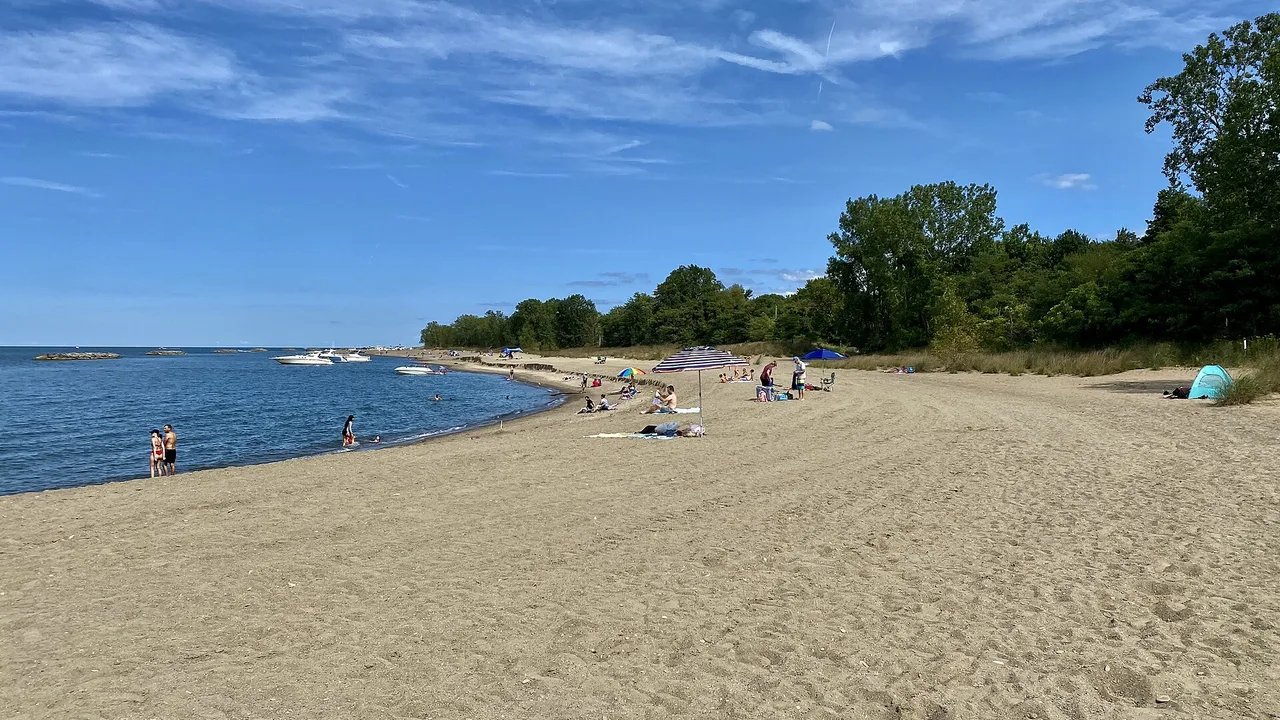 Sunbathers, umbrellas and anchored boats along the sandy shore of Leslie Beach at Presque Isle State Park, Erie, Pennsylvania, on Lake Erie