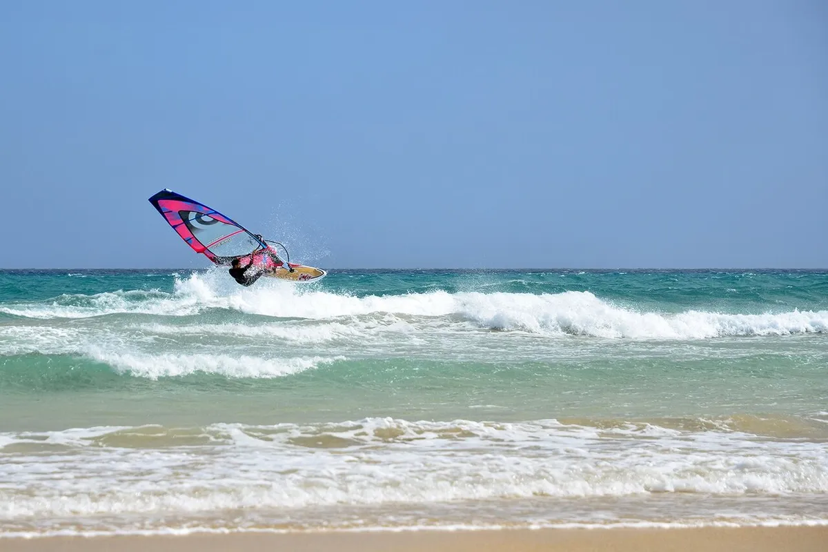 Planchiste décollant d'une vague sous un ciel bleu dégagé, à la plage de Sotavento, à Fuerteventura