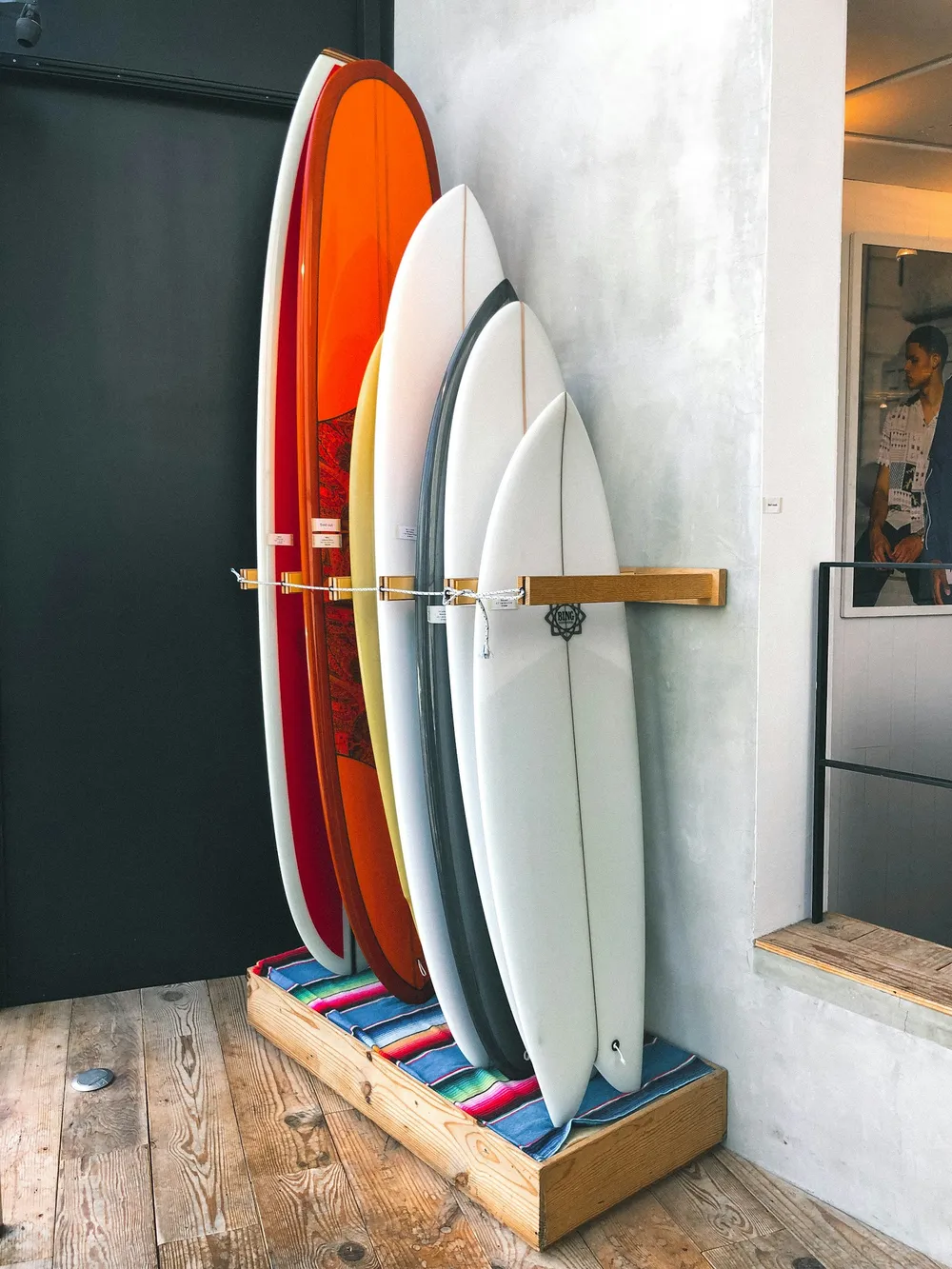Varias tablas de surf de distintas longitudes y formas colocadas en vertical en un expositor de madera