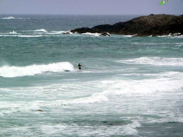 A kitesurfer riding between breaking waves off Balevullin, Tiree