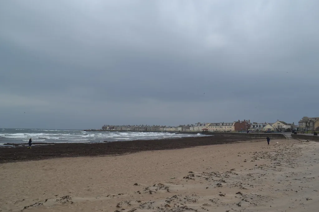 The long sandy strand at South Beach, Troon, under a grey sky, with the seafront terraces along the shore behind