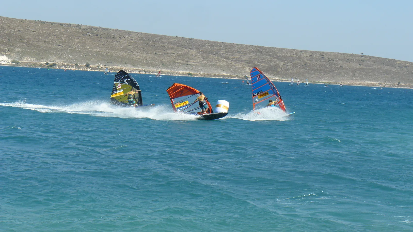 Three windsurfers racing round a buoy in Alaçatı Bay during the 2014 Windsurf World Cup