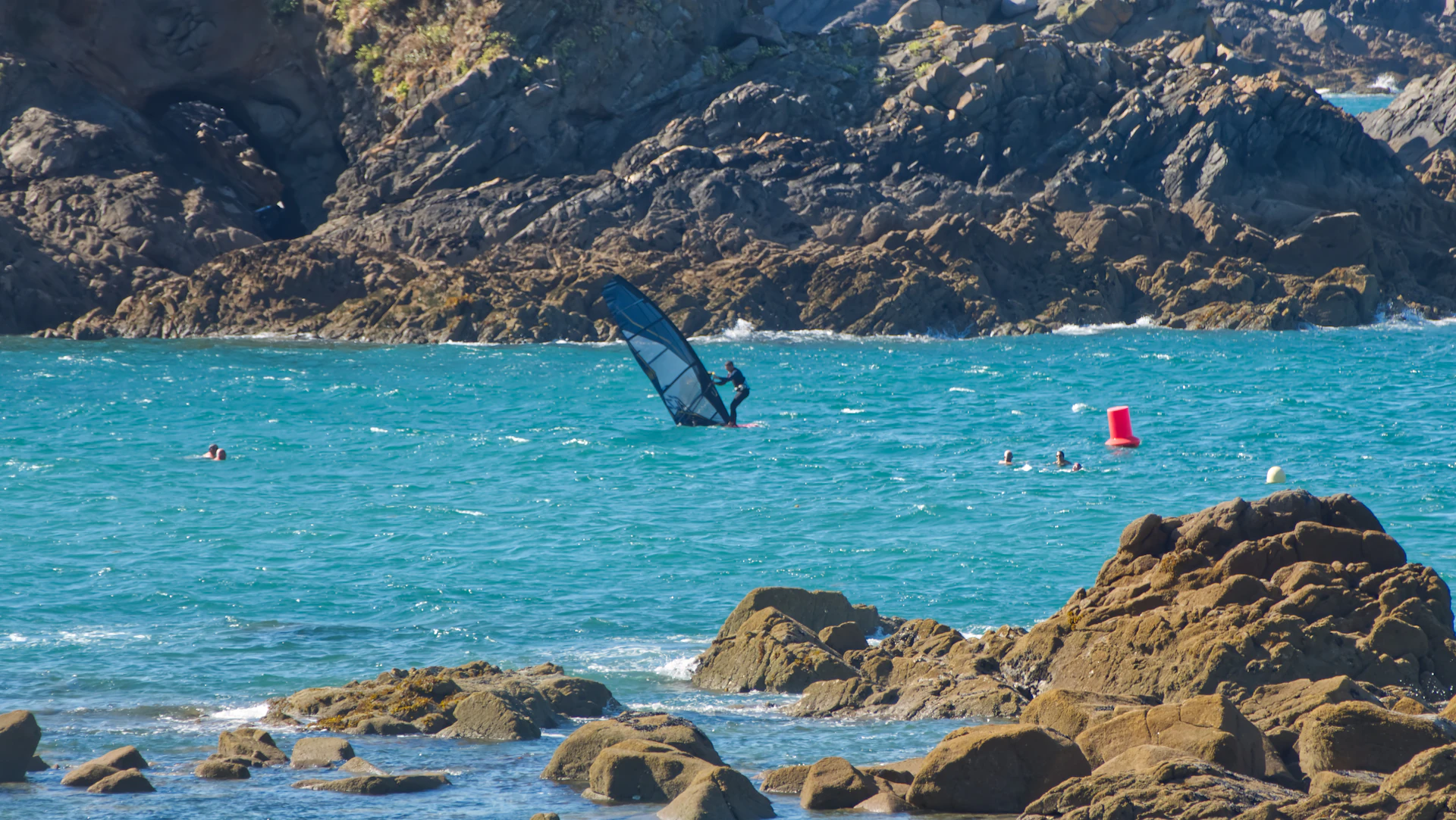 Windsurfeur naviguant le long d'une côte rocheuse en France